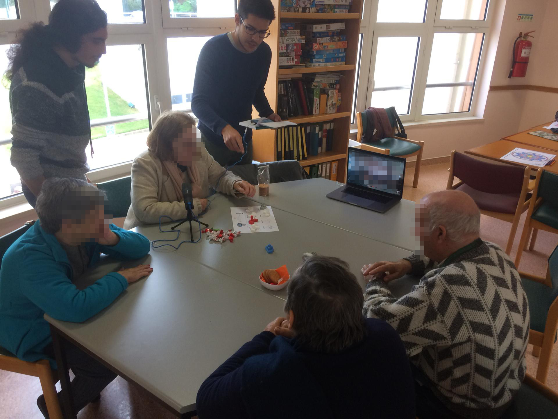 Photo taken from the Workshop with elderly people. Two people are interacting with the carrier robot
