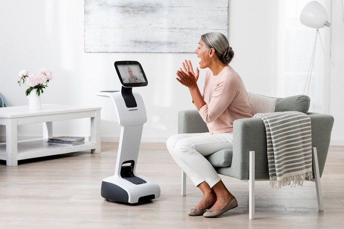 An older woman interacting with a Temi robot