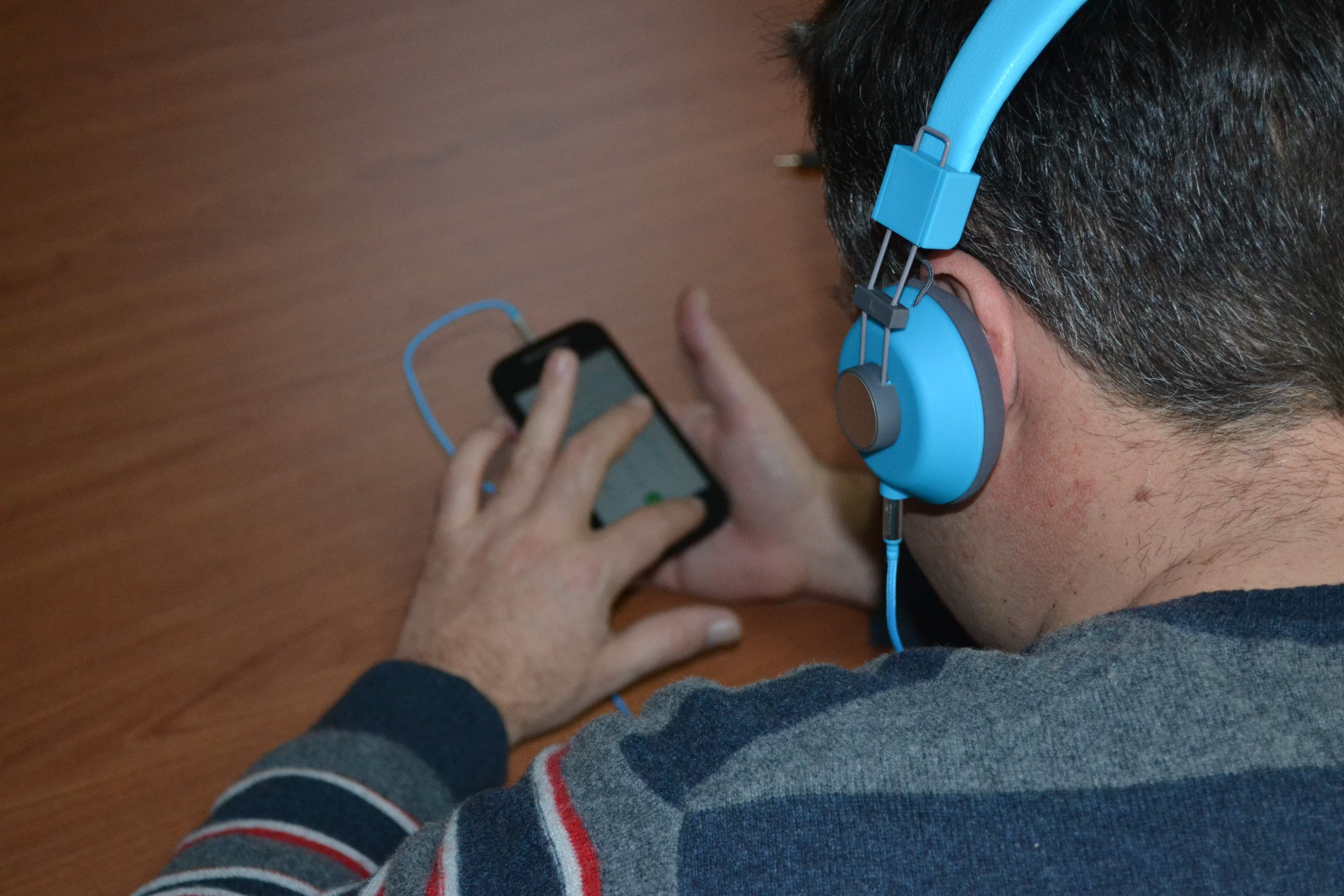 A blind person interacting with a smartphone using headphones.