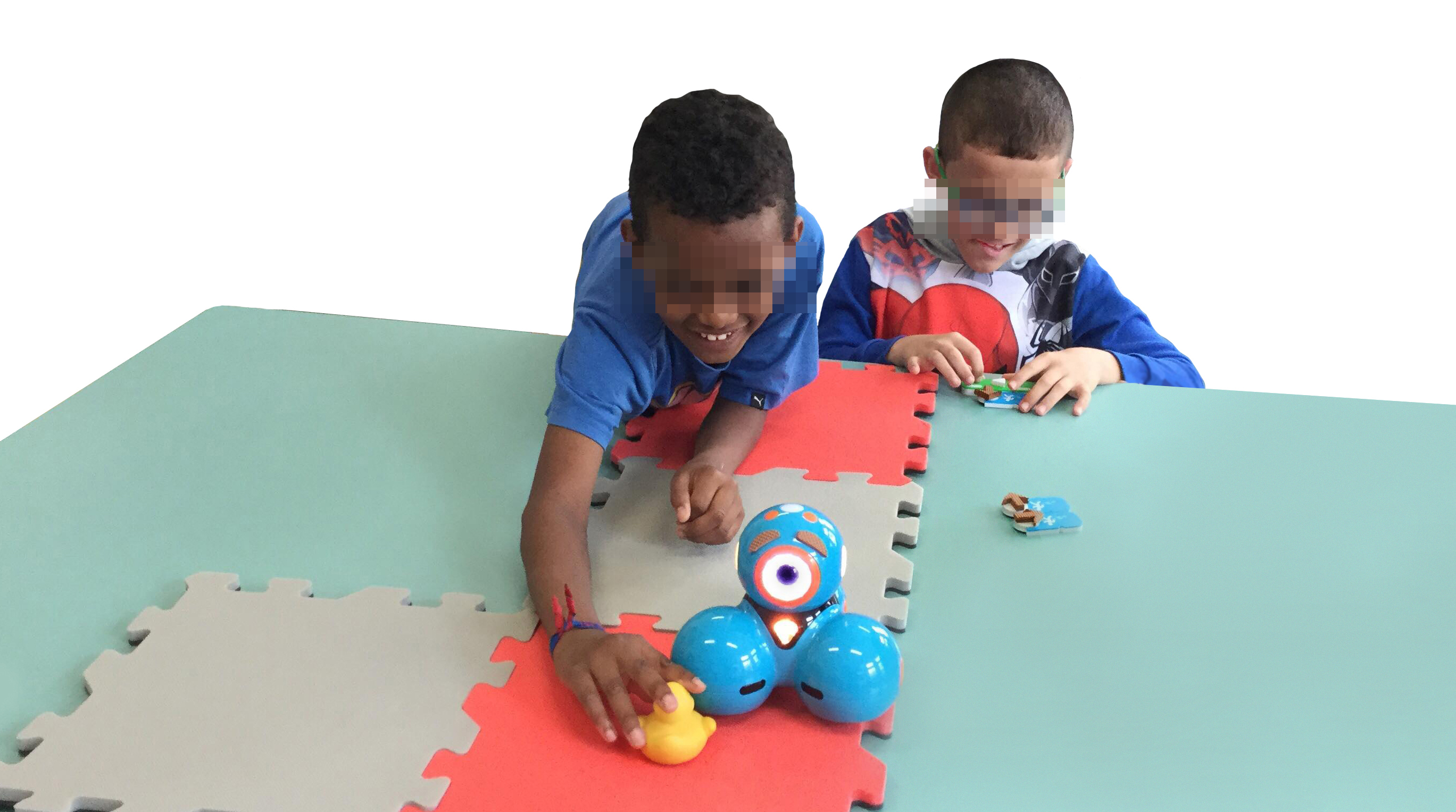 Two children with visual impairments, one attaching a forward and play pieces, and the other feeling the robot and the target object, that walked through a foam path.