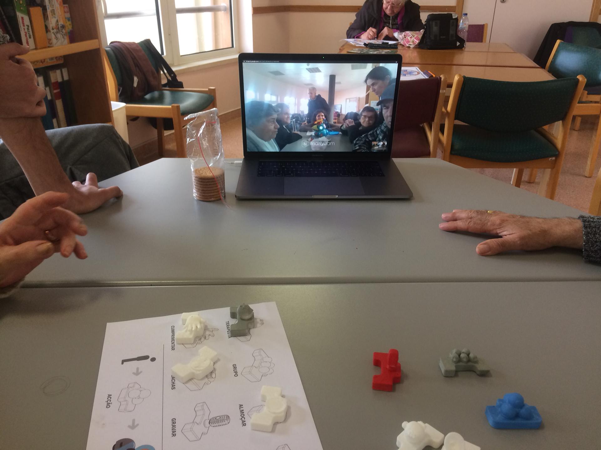 Activity in a care home where a group of older adults is working on a table and watching the other group through a video call