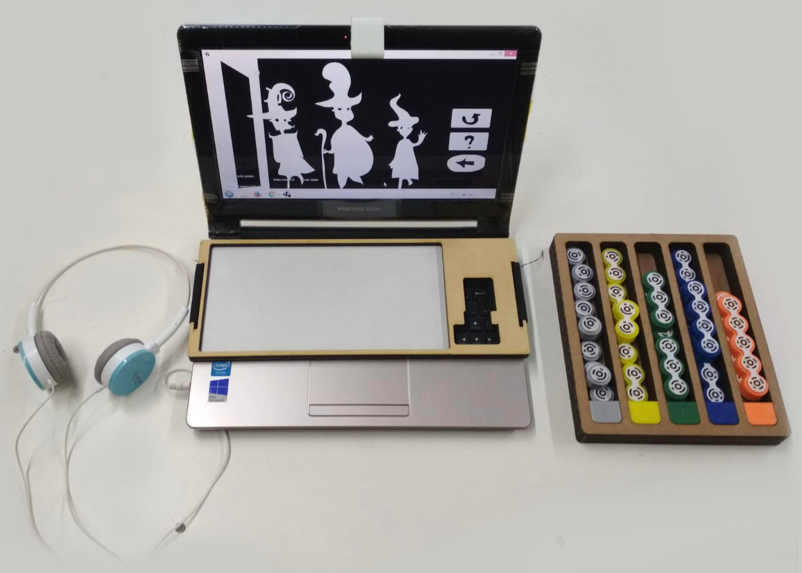 Computer with headphones and a tray on top and a set of tangible blocks on the side
